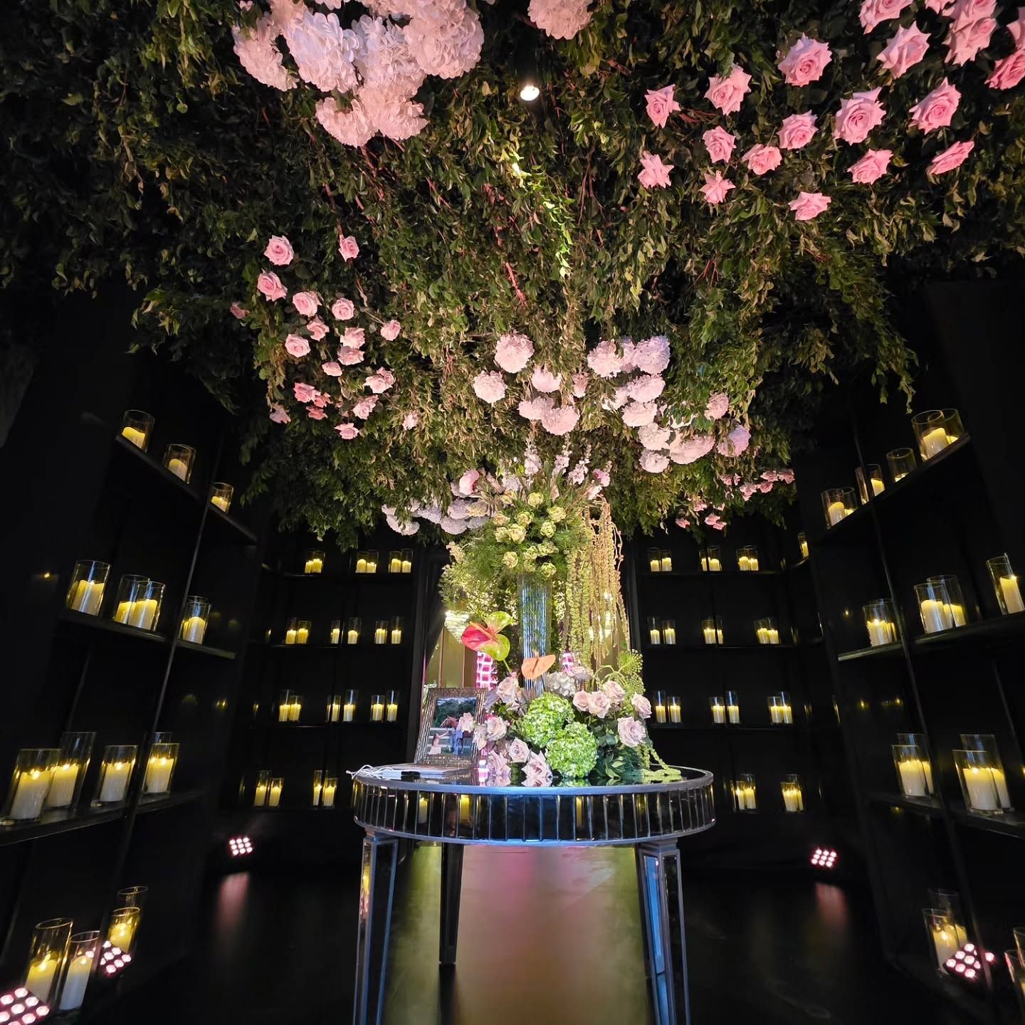 Árbol floral con flores rosadas iluminado sobre una mesa, rodeado de velas