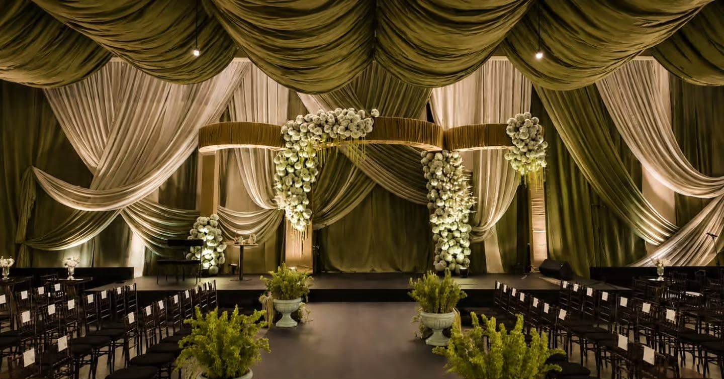 Altar con arcos florales entre cortinas iluminadas
