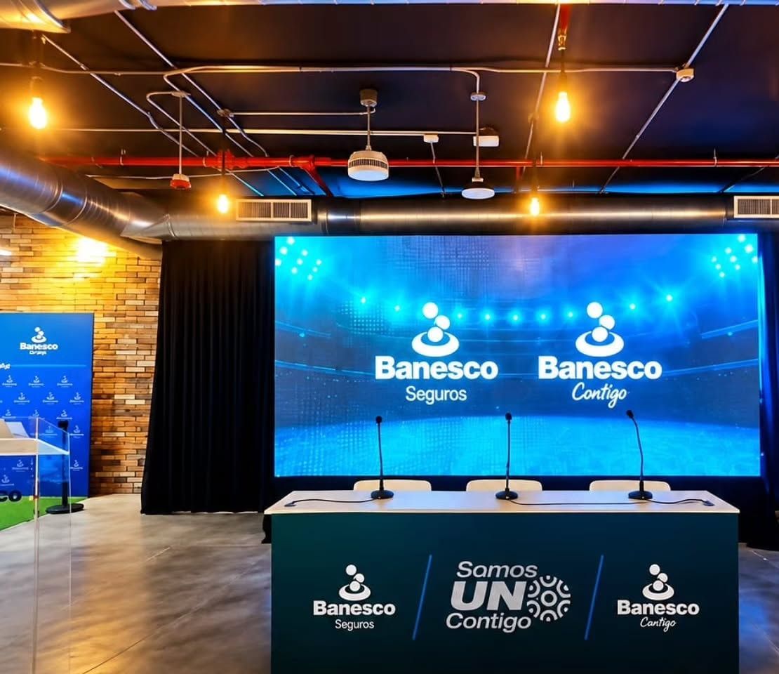 Pantalla LED detrás de una mesa de panel con tres micrófonos