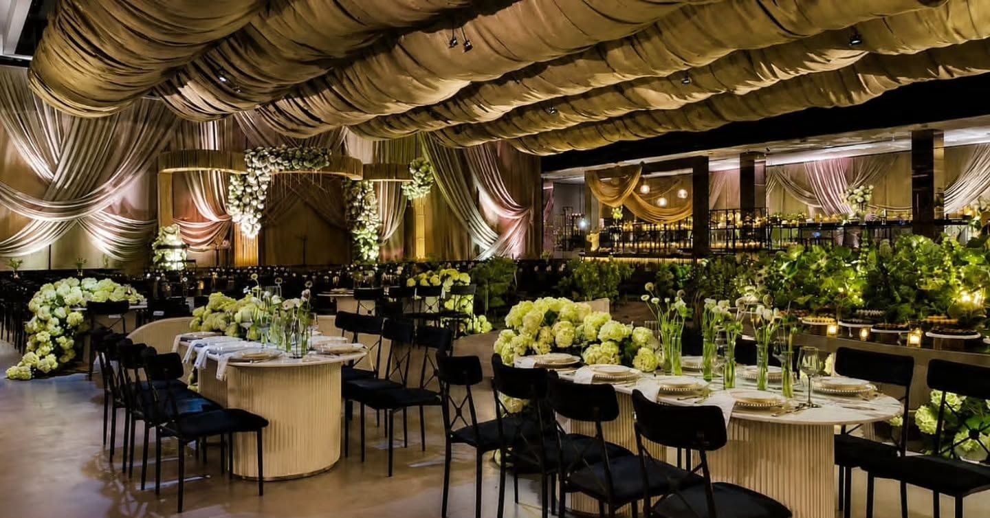 Salón de recepción con mesas redondas, flores y techo de telas