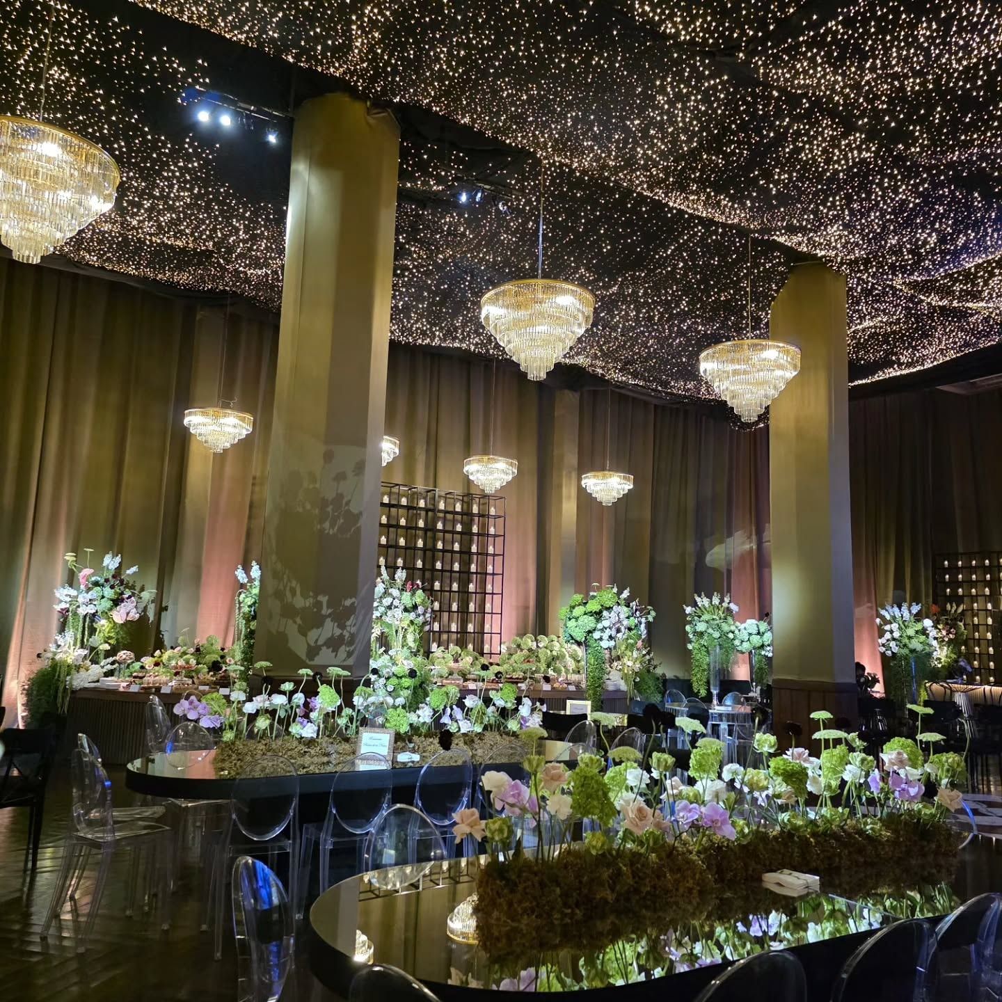 Mesas de boda con centros florales bajo candelabros iluminados