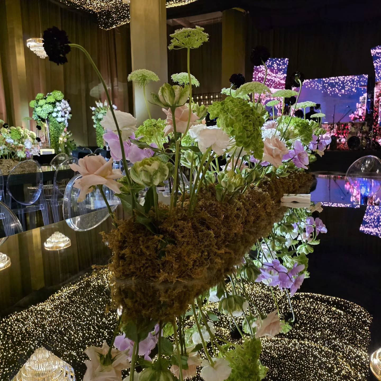Detalle de centro floral de musgo con el techo de luces al fondo